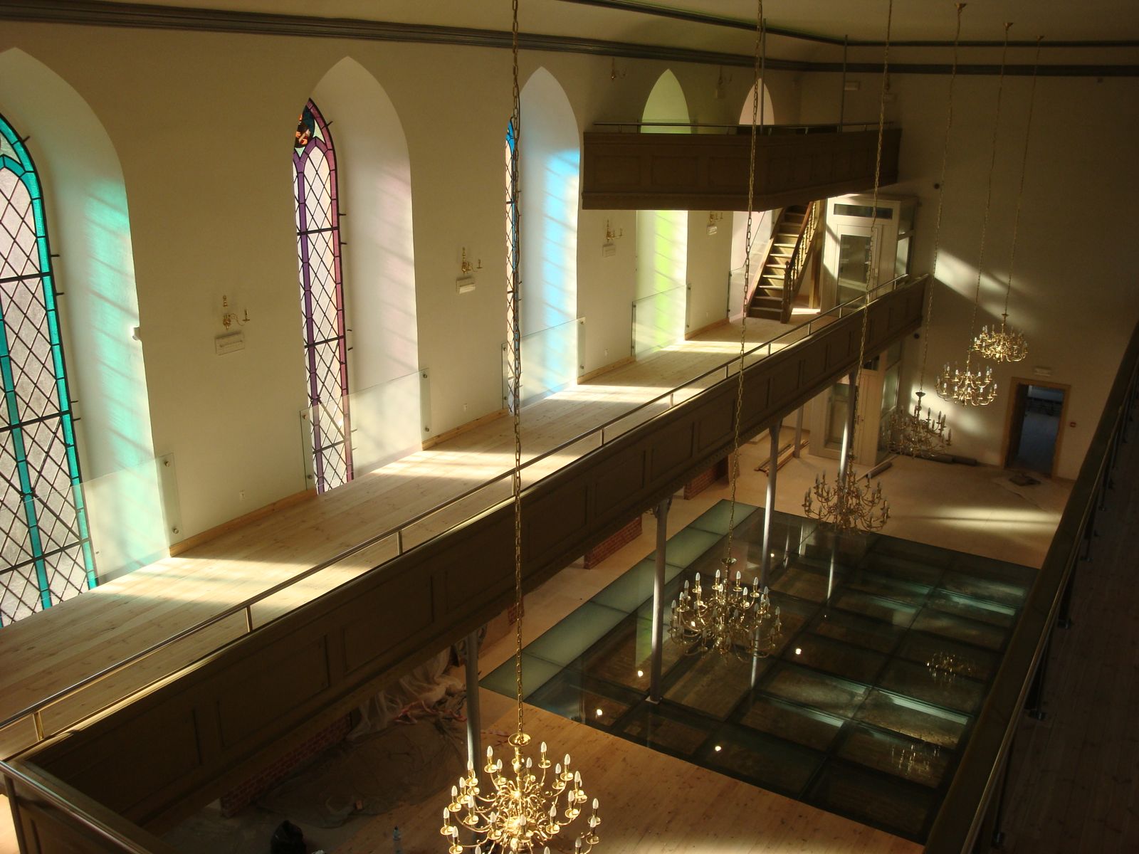 Galeria w zabytkowym wnętrzu z witrażami, szklane balustrady wzdłuż antresoli